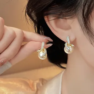 Primo piano di eleganti orecchini a perno con perle placcate oro 18 carati e zirconi sul lobo.