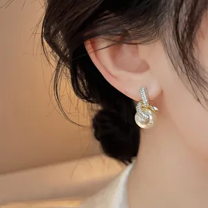 Dettaglio di eleganti orecchini placcati oro 18K con zirconi e pendente di perla