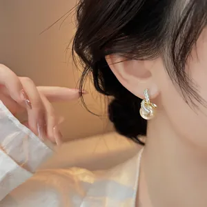 Elegante orecchino di perla placcato oro 18 carati con nodo di zircone su modella