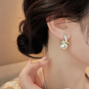 Dettaglio ravvicinato di un elegante orecchino a bottone in zircone e perla placcato 18K.