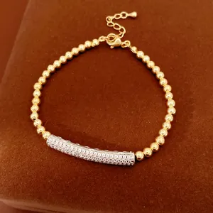 Detailed view of elegant gold beaded bracelet with a zircon-inlaid silver curved bar.