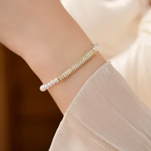 Close-up detail of a gold zircon-paved bamboo charm on a dainty pearl strand bracelet