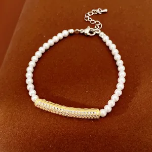 Detailed view of elegant pearl bracelet featuring a zircon-inlaid golden curved bar accent