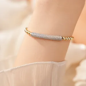 Detailed macro view of an elegant gold beaded bracelet with shimmering cubic zirconia inlay