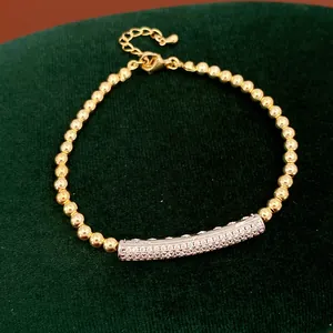 Detailed macro view of a zircon-inlaid gold bead bracelet on a green velvet background