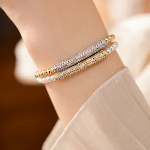 Close-up detail of zircon-inlaid bamboo bar pearl and gold beaded bracelets.