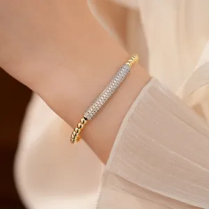Close-up of elegant zircon pavé bar and gold beaded adjustable bracelet on model wrist