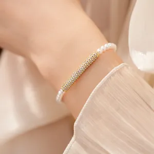Detail view of gold-plated bamboo bar bracelet with sparkling zircons and white pearls