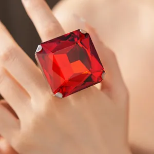 Macro view of an oversized square red faceted gem ring worn on a hand showing cut details
