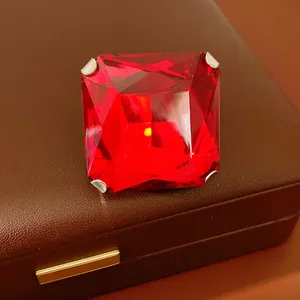 Close-up of large red square faceted gemstone earring on brown jewelry box.