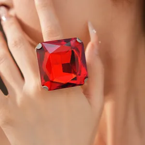 Detailed macro shot of a large square faceted red crystal cocktail ring worn on a finger