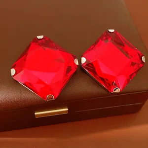 Detailed close-up view of large red square faceted crystal stud earrings on a brown box.