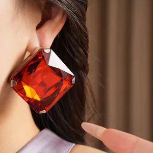 Close-up of a large square red crystal earring worn on an ear for a luxury look.