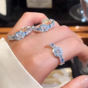 Detail shot of an elegant square zircon ring and C-shaped earrings on an Asian hand
