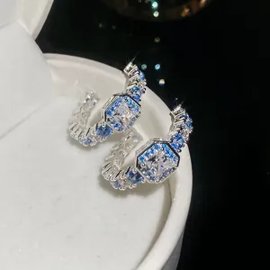 Macro view of C-shaped hoops with blue and white square cubic zirconia stones