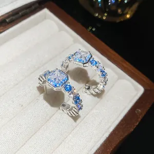 Detailed macro shot of C-shaped hoop earrings featuring blue and clear zircon stones