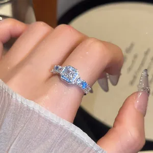 Close-up detail of a silver-tone ring featuring a square zircon and blue accent stones.