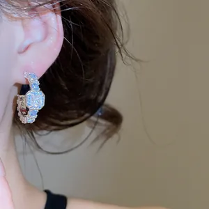 Detailed close-up showing sparkling silver square zircon C-shaped hoop earrings on ear