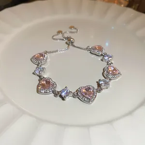 Gros plan d'un bracelet scintillant avec zircons en forme de cœur rose sur une assiette.