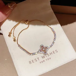 Détail d'un bracelet vintage avec trèfle en zircon rose sur un petit pochon de cadeau blanc