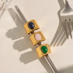 Detail of three gold vintage rings with colorful oval gemstones on a metal rod