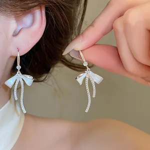 Detailed shot of sparkling zircon bow earrings with white enamel finish