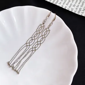 Elegant silver metal drop earrings with zircon accents and long beaded tassels on white shell