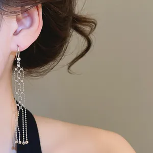 Close-up of elegant silver tassel earrings with zircon accents on model ear