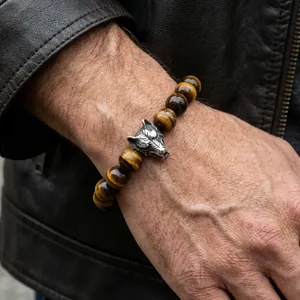 Men's natural tiger eye beaded bracelet with vintage silver wolf head on leather background