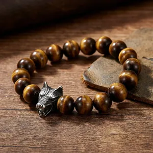 Detailed shot of yellow tiger eye beads and silver wolf head charm on wooden table