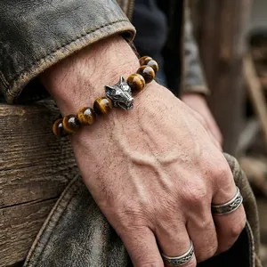 Close-up of a tiger eye bead bracelet with an antique silver wolf head charm on a wrist