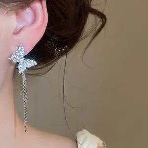 Macro detail view of a sparkling silver butterfly earring with elegant zircon stones and tassels.