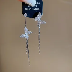 Detailed view of asymmetrical butterfly drop earrings with shimmering zircons.