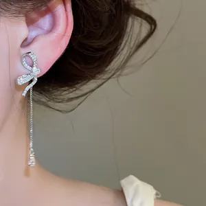 Detailed macro view of elegant zircon bow earrings with long dangling silver chain