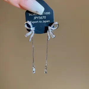 Detailed macro shot of sparkling zircon bow knot earrings with silver chain tassels