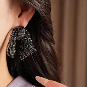 Dettaglio ravvicinato di eleganti orecchini a fiocco neri con strass su una modella