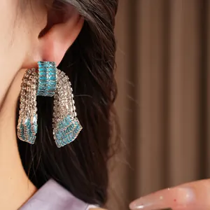 Dettaglio orecchini a fiocco blu con strass brillanti indossati da una modella.