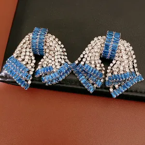 Dettaglio di orecchini a fiocco vintage con pietre di zircone blu e trasparenti.