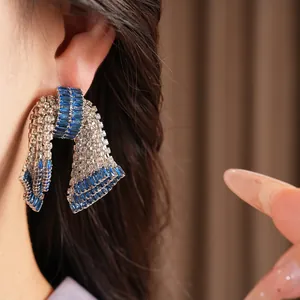 Primo piano di un lussuoso orecchino a fiocco con zirconi blu e argento indossato