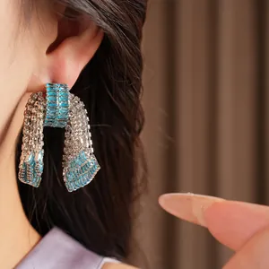 Primo piano dettagliato di orecchini a fiocco vintage con zirconi blu su modella