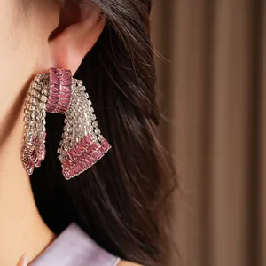 Dettaglio macro di orecchini a fiocco vintage con zirconi rosa e ago d'argento