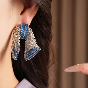 Dettaglio ravvicinato di orecchini a fiocco vintage con pietre di zircone blu e trasparenti