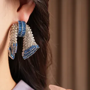 Dettaglio di orecchini a fiocco vintage con zirconi blu e bianchi su un orecchio