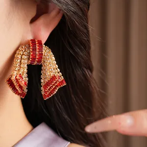 Dettaglio degli orecchini a fiocco vintage con pietre di zircone rosse e trasparenti.
