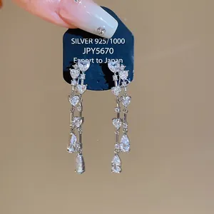 Dettaglio di orecchini a clip con nappe in zircone a cuore e goccia scintillanti