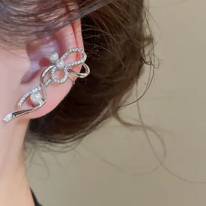 Dettaglio dell'elegante clip da orecchio a fiocco in argento con zirconi e perle