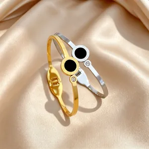 Close-up of gold and silver titanium steel bangles with Roman numerals and zircon