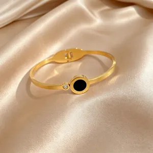 Close-up of gold titanium steel bangle with Roman numerals and black circular inlay.