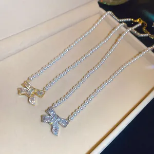 Detailed macro shot of 18k gold plated bow pendant pearl necklaces inside a jewelry gift box