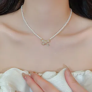 Detail of elegant pearl necklace featuring a sparkling zircon bow pendant on a model